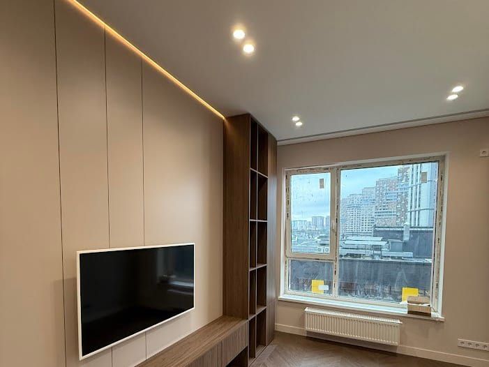 Televize zavěšená na obkladové stěně v obývacím pokoji